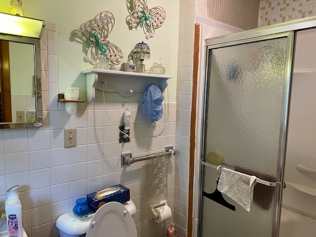 bathroom featuring tile walls, a shower with shower door, and toilet