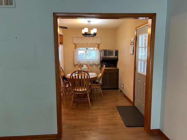 dining space featuring a notable chandelier, light wood-type flooring, and a healthy amount of sunlight