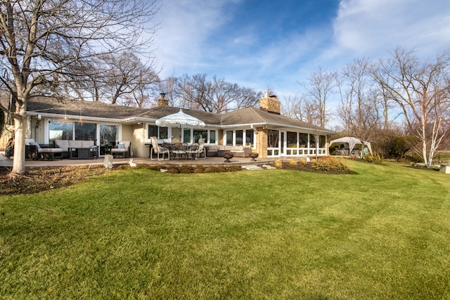 rear view of property with an outdoor living space, a patio area, and a lawn