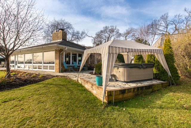 back of property featuring a hot tub, a yard, and a patio