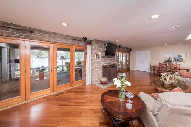 living room with a large fireplace, wood-type flooring, and french doors