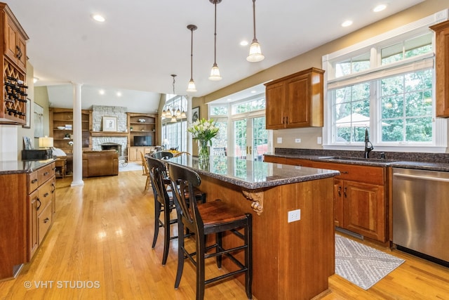 kitchen featuring dishwasher, light hardwood / wood-style floors, a kitchen island, and a fireplace