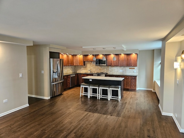 kitchen featuring pendant lighting, sink, a center island, appliances with stainless steel finishes, and dark wood-type flooring