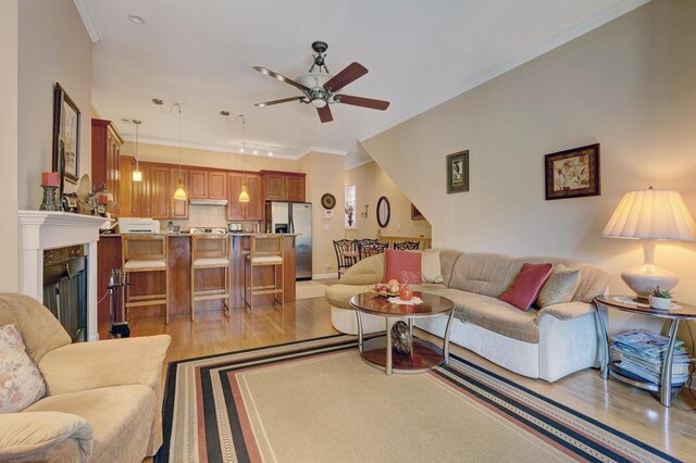 living room with light hardwood / wood-style floors, crown molding, and ceiling fan