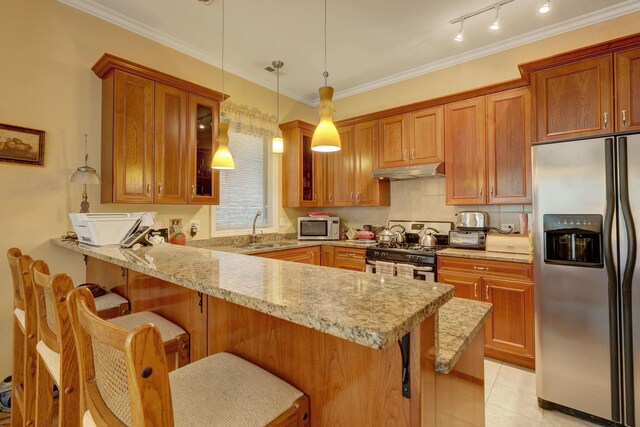 kitchen with decorative light fixtures, a kitchen bar, appliances with stainless steel finishes, kitchen peninsula, and backsplash