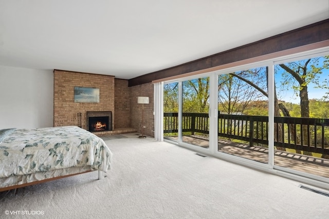 carpeted bedroom with access to exterior and a fireplace