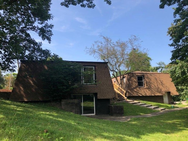 rear view of property with stairway and a yard