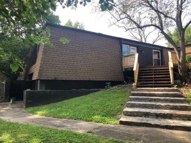 view of front of home with roof with shingles, stairway, and a front lawn