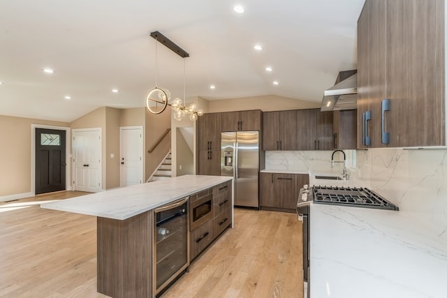 kitchen featuring light wood-type flooring, wine cooler, a center island, hanging light fixtures, and stainless steel appliances