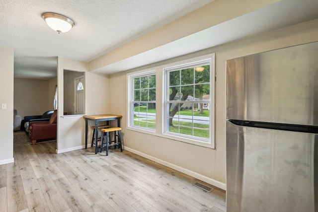 dining space featuring light hardwood / wood-style floors and a textured ceiling