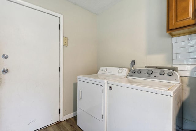 laundry area with dark hardwood / wood-style flooring, washer and clothes dryer, and cabinets