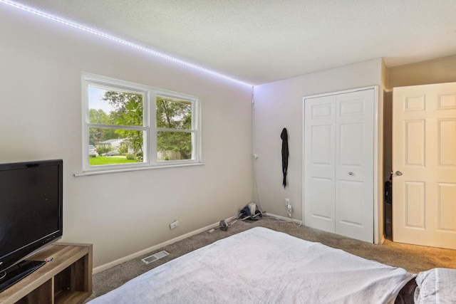 bedroom featuring carpet floors, a textured ceiling, and a closet