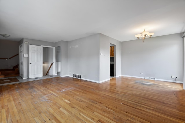 unfurnished living room featuring an inviting chandelier and hardwood / wood-style flooring