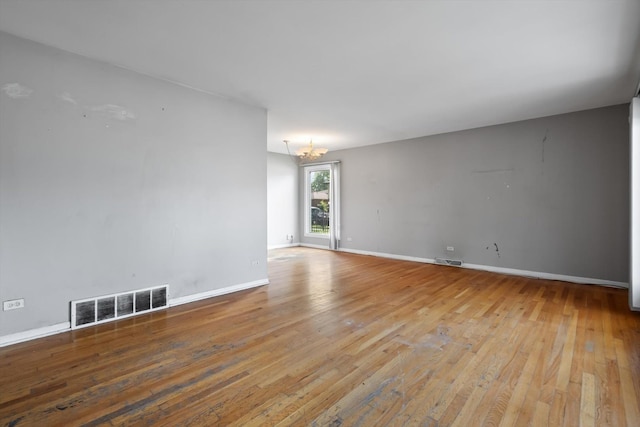 unfurnished room with a chandelier and light wood-type flooring