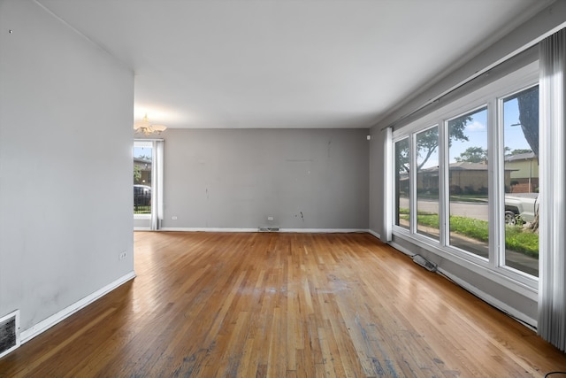 unfurnished room featuring an inviting chandelier and wood-type flooring