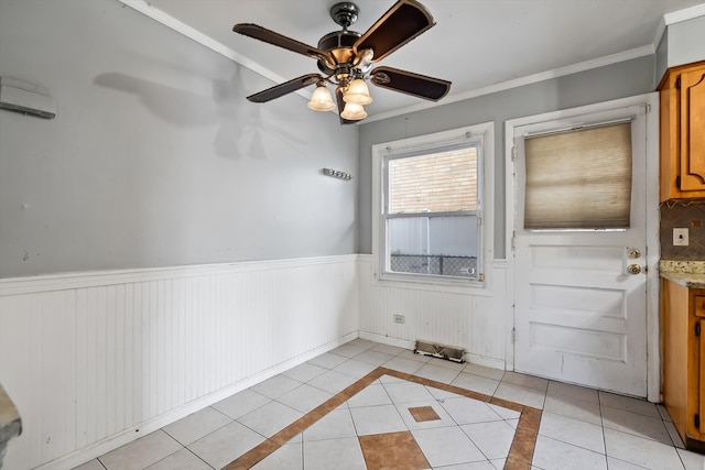 tiled empty room with ornamental molding and ceiling fan