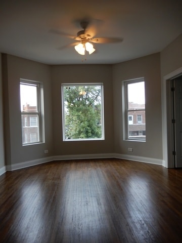 spare room featuring a healthy amount of sunlight, ceiling fan, and dark hardwood / wood-style floors