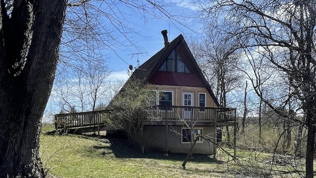 back of property with a deck and a lawn