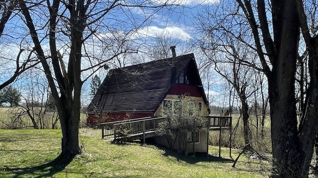 view of side of home with a deck and a lawn