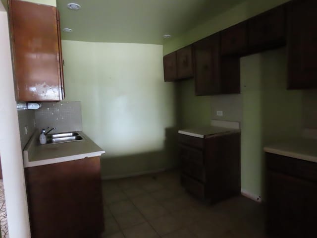 kitchen featuring sink, decorative backsplash, dark brown cabinets, and light tile patterned floors