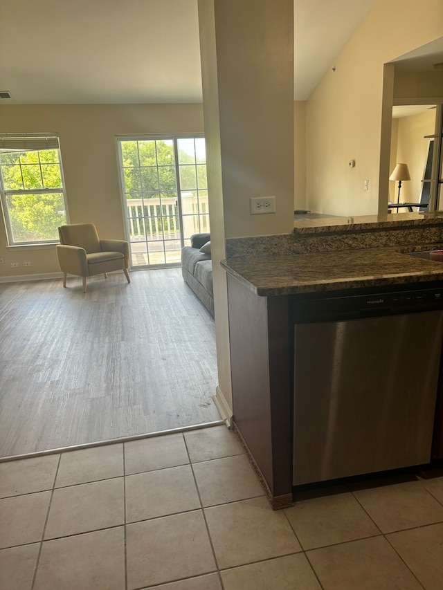 kitchen with dishwasher, light tile patterned floors, and vaulted ceiling