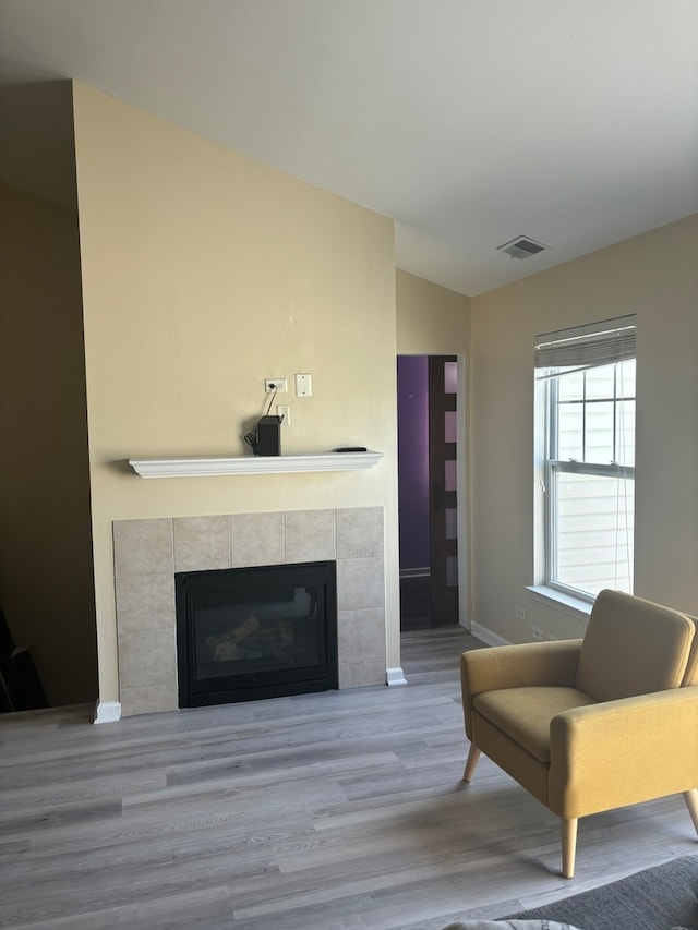 living room with vaulted ceiling, a fireplace, and hardwood / wood-style floors