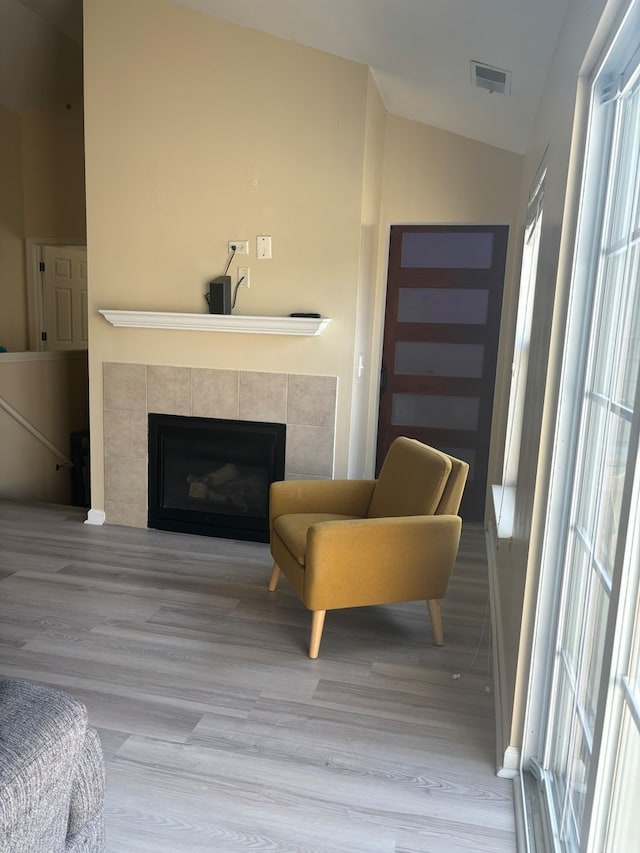 sitting room with a fireplace, vaulted ceiling, and hardwood / wood-style floors