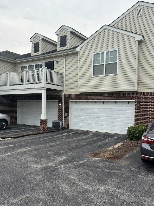 view of front facade with a garage, a balcony, and central air condition unit