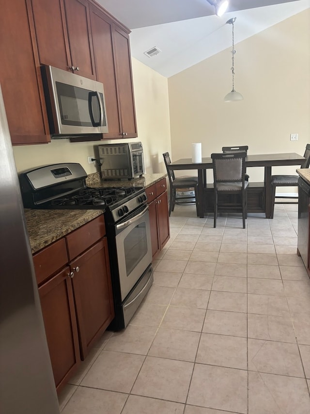 kitchen featuring appliances with stainless steel finishes, pendant lighting, dark stone counters, and light tile patterned floors