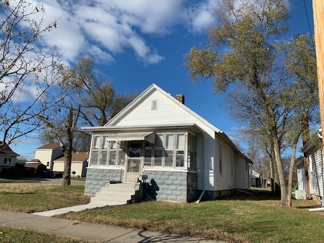 bungalow with a front yard and a sunroom