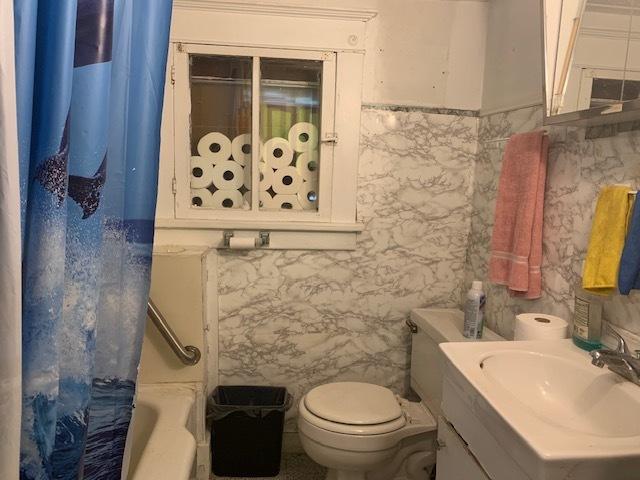 full bathroom featuring tile walls, shower / bath combo, toilet, and vanity