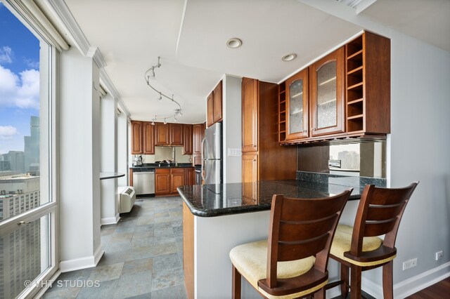 kitchen featuring appliances with stainless steel finishes, kitchen peninsula, a kitchen breakfast bar, tile patterned floors, and track lighting