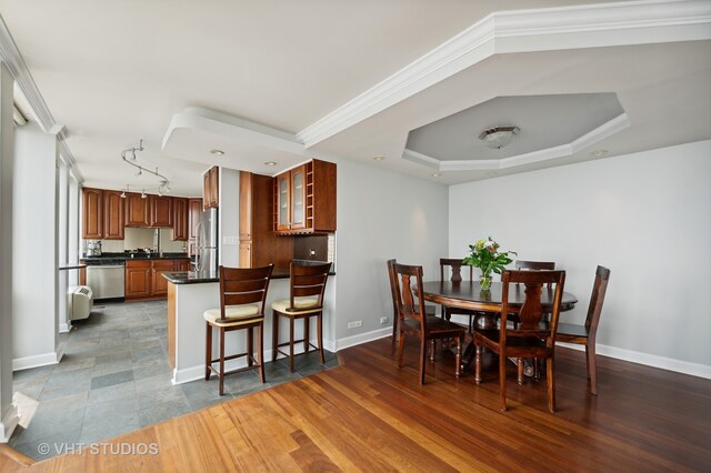 tiled dining room with crown molding, a tray ceiling, and rail lighting