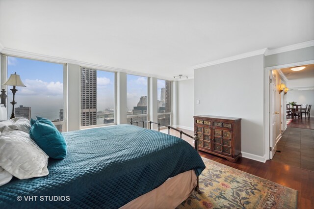 bedroom with dark wood-type flooring, track lighting, and crown molding