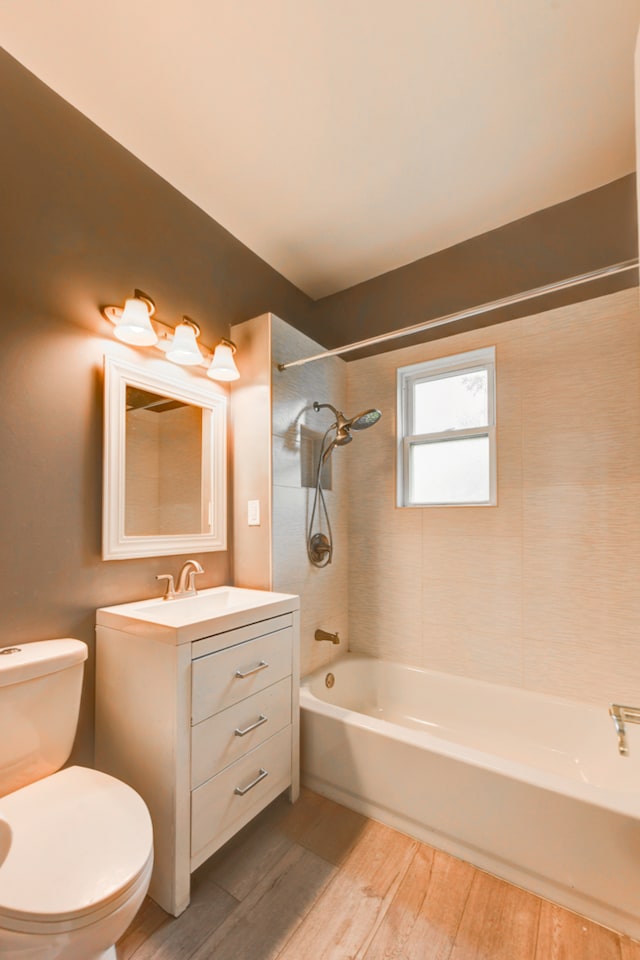 full bathroom with vanity, tiled shower / bath, hardwood / wood-style floors, and toilet