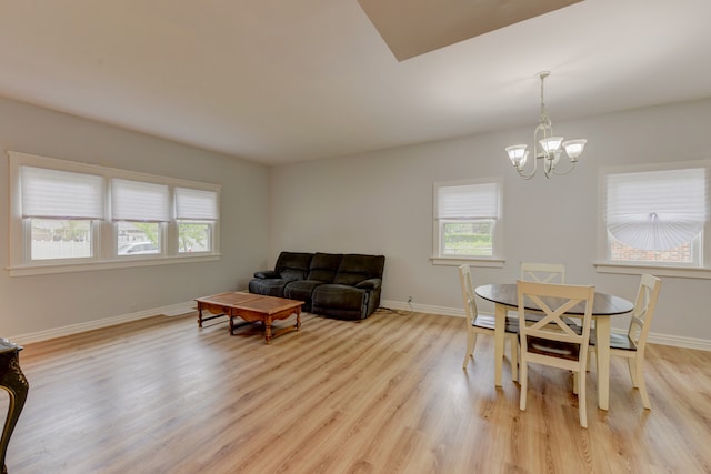 dining space with light hardwood / wood-style floors and an inviting chandelier