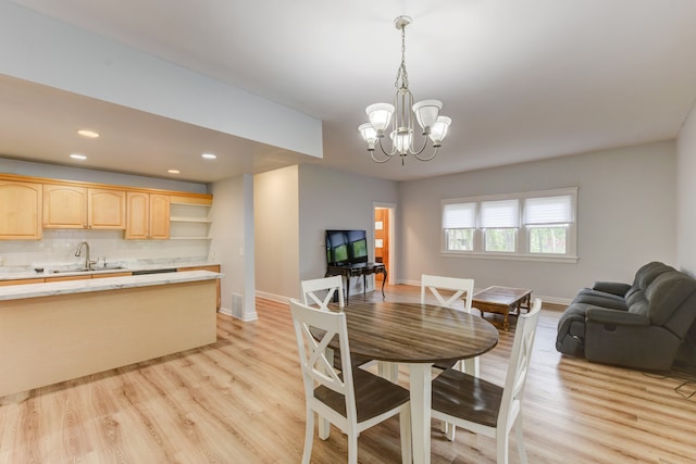 dining room featuring light hardwood / wood-style floors, sink, and an inviting chandelier