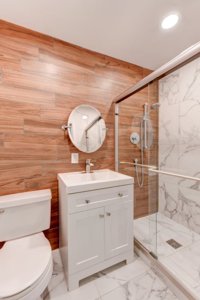 bathroom with a shower with door, toilet, vanity, tile walls, and tile patterned floors