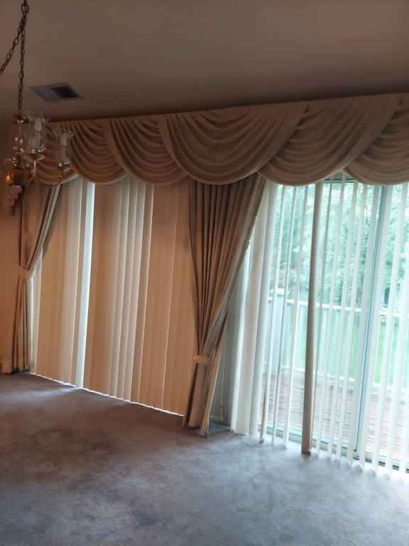 unfurnished room featuring carpet flooring and a chandelier