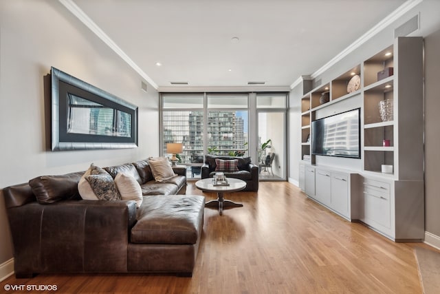 living room featuring light hardwood / wood-style floors, crown molding, and built in features