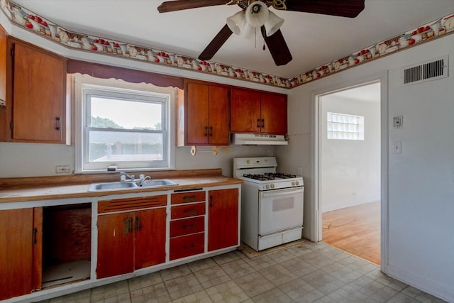 kitchen featuring sink, ceiling fan, white gas range oven, and light tile patterned floors