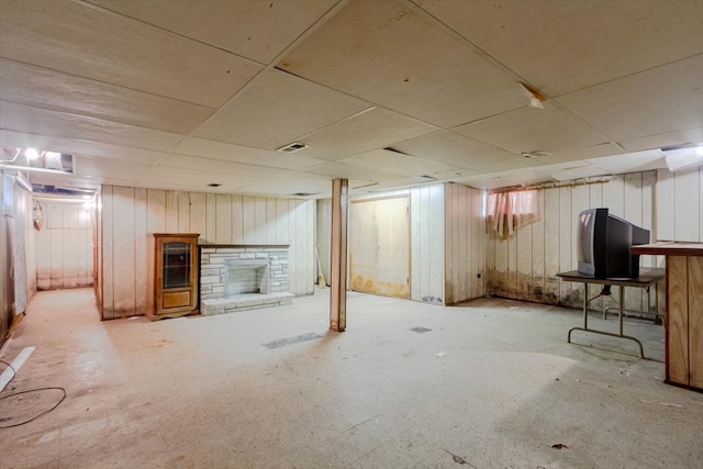 basement featuring a drop ceiling and a stone fireplace