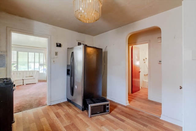 hallway with light colored carpet and a chandelier