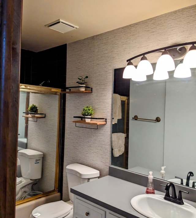 full bathroom featuring vanity, combined bath / shower with glass door, and toilet