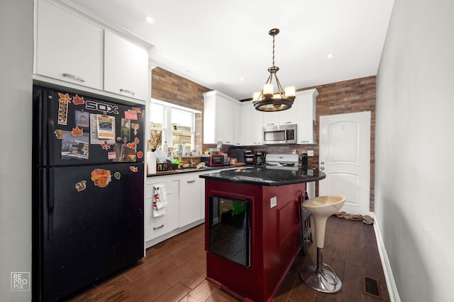 kitchen with white cabinetry, range, a kitchen island, and black fridge