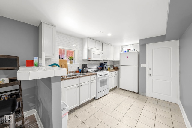 kitchen with white appliances, tile countertops, sink, and white cabinets