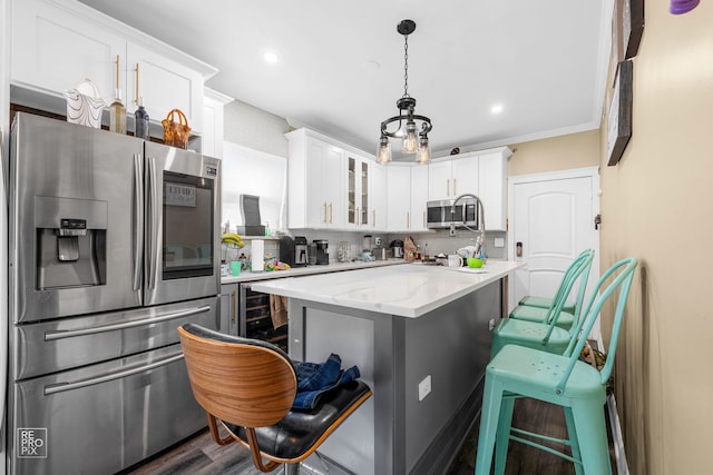 kitchen with a breakfast bar area, white cabinetry, decorative light fixtures, appliances with stainless steel finishes, and light stone countertops