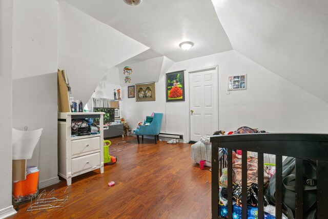 bedroom with a baseboard radiator, lofted ceiling, and hardwood / wood-style flooring