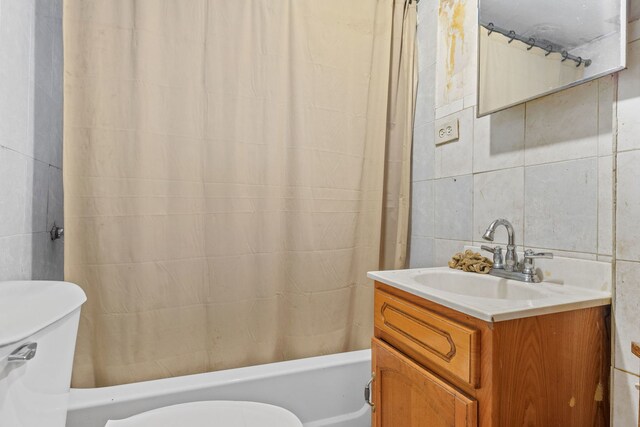 full bathroom with tile walls, shower / bath combination with curtain, toilet, and vanity