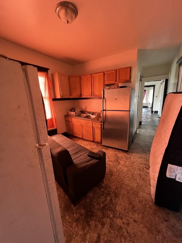 kitchen featuring tile patterned flooring, stainless steel refrigerator, and sink